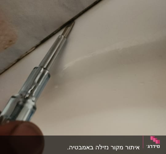 מברג נוגע בקצה תקרה לבנה לבדוק נזילות